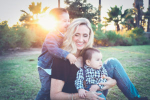 Mother and two children playing outside on a sunny day.