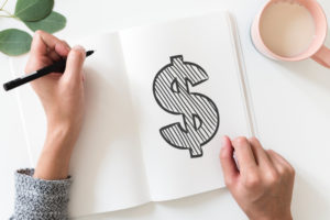 Person drawing money sign in notebook